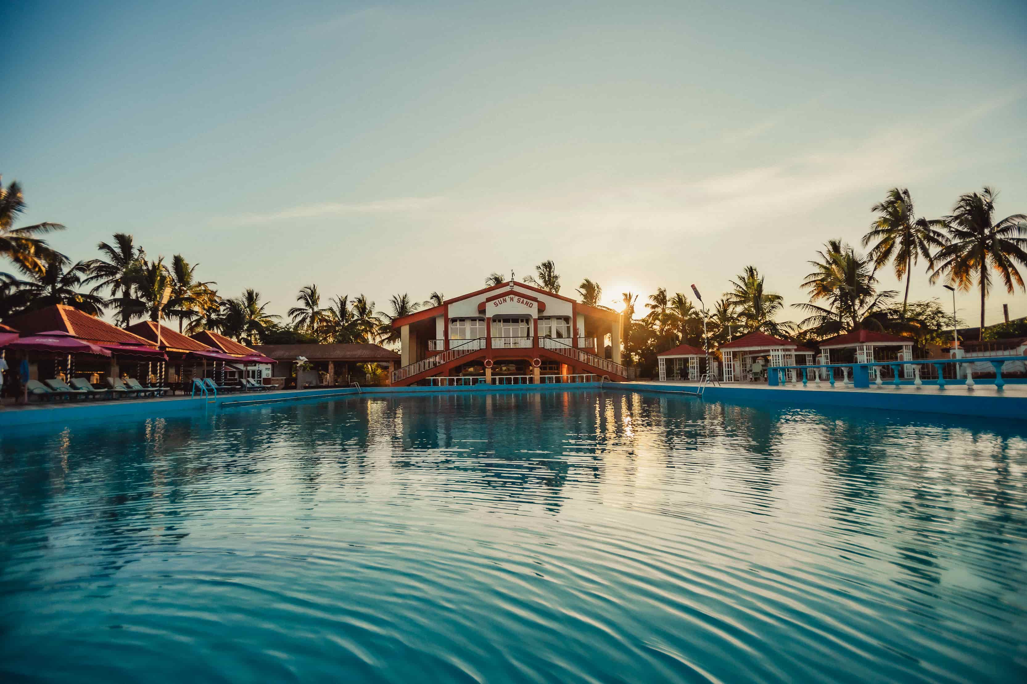 view of swimming pool facing towards building with sun n sand sign
