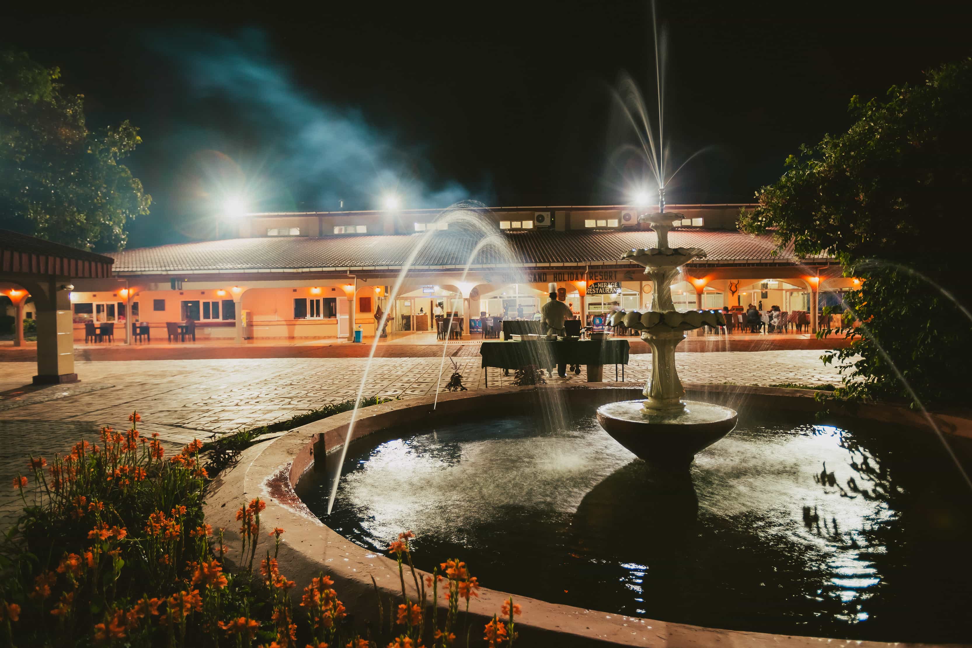 close up fountain facing restaurant with chef grilling
